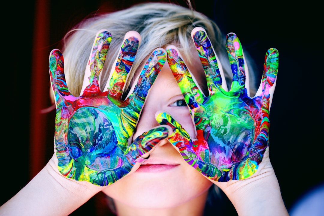 child with colored hands outside