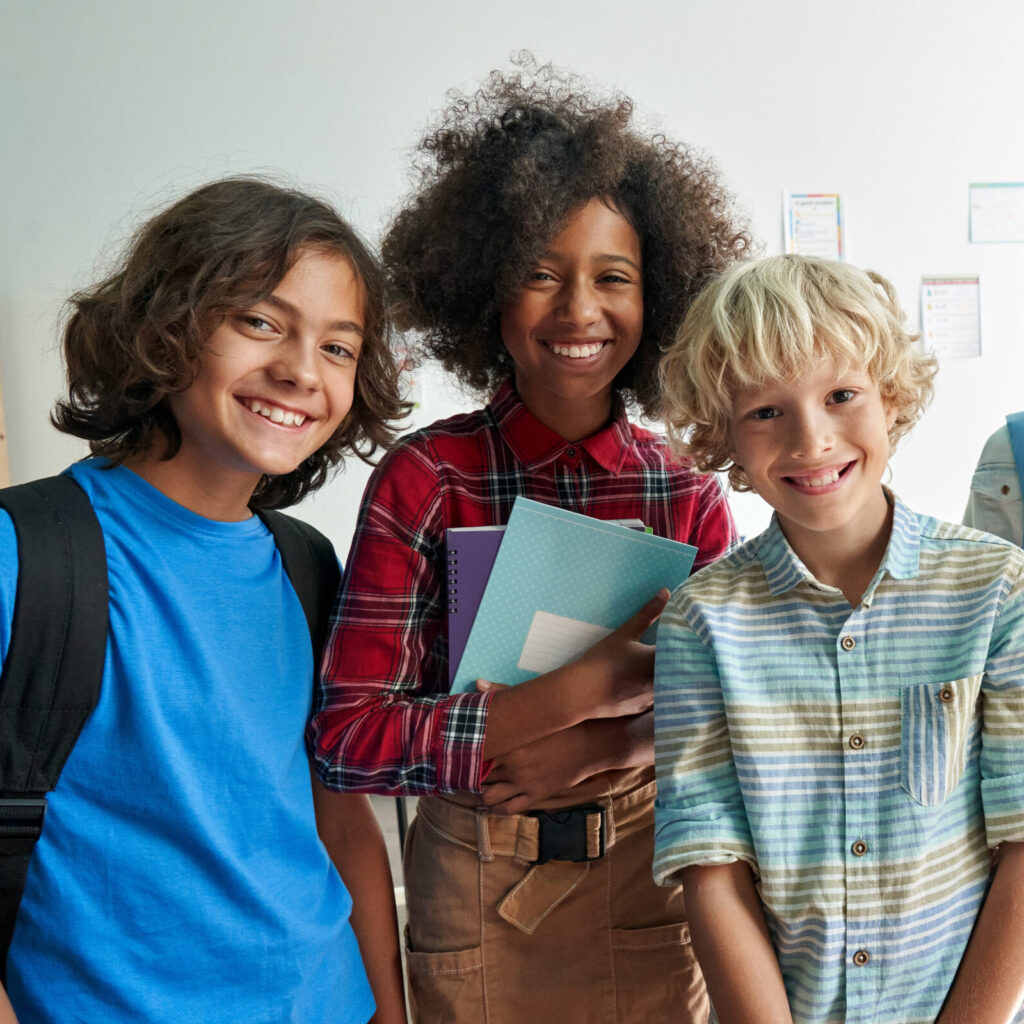 Happy diverse students standing in classroom.